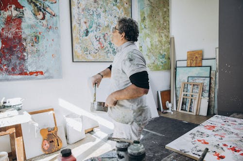 A man in an art studio with a painting on the wall