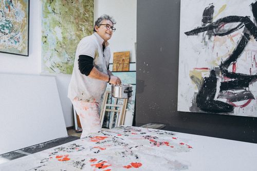 Free An artist joyfully creating a large abstract painting in a vibrant art studio. Stock Photo