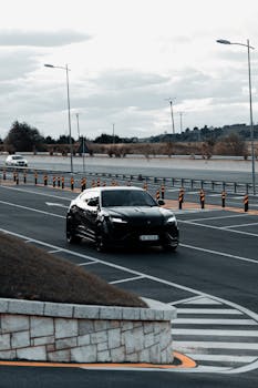 Luxury car driving on a modern highway in Tirana, Albania, with cloudy skies and minimal traffic.