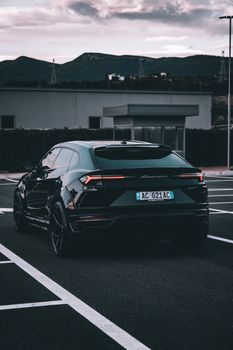 Elegant Lamborghini Urus parked in a Tirana parking lot, set against mountain backdrop.