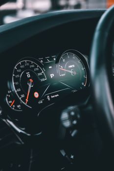 Close-up of a sleek car dashboard with illuminated speedometer and gauges.