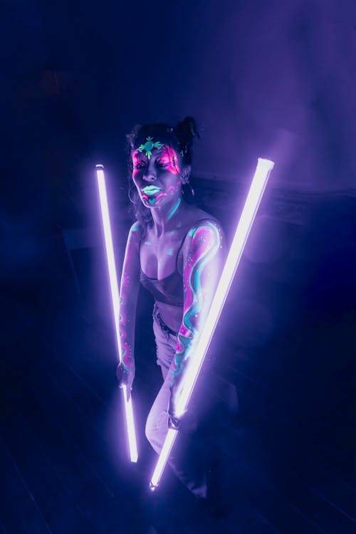 Woman in a Fluorescent Makeup Holding Neon Purple Lights