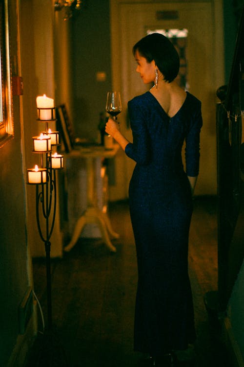 A woman in a blue dress holding a glass of wine