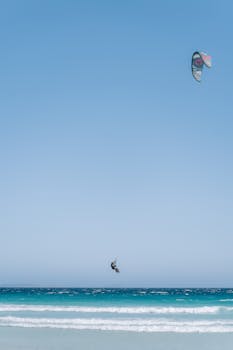 Kitesurfer catching air over the turquoise waves in Esperance, Australia, under a clear sky.