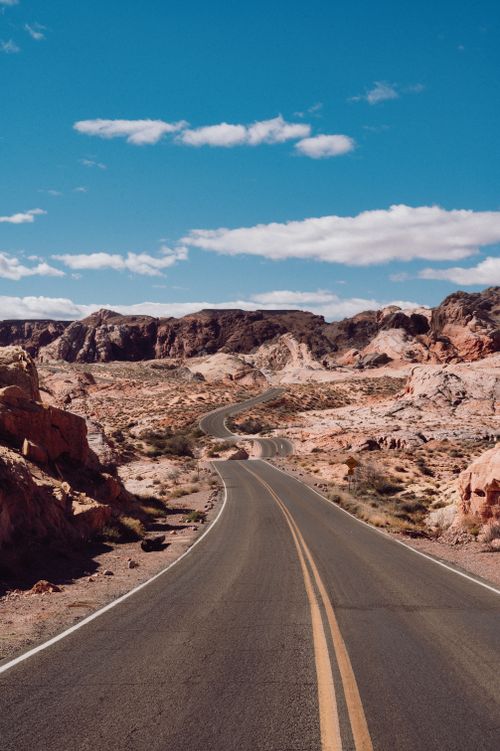 Free Scenic view of a winding road through rocky desert terrain under a clear blue sky. Stock Photo