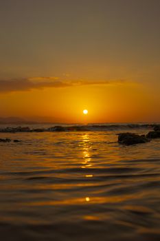 A tranquil sunset scene with golden hues reflecting over gentle ocean waves, capturing serene natural beauty.