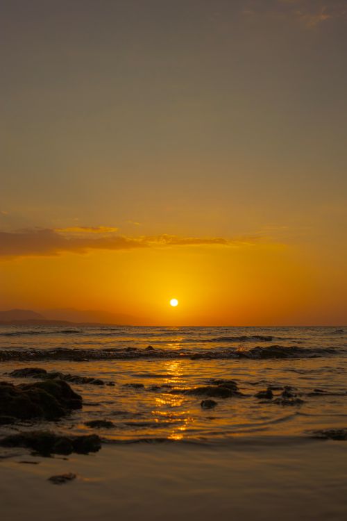 Free Breathtaking sunset over a tranquil beach with golden reflections on the sea. Stock Photo