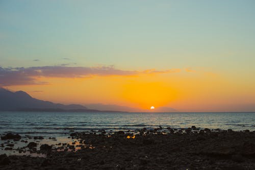 A sunset over the sea with mountains in the background