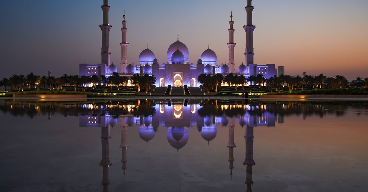 The magnificent Sheikh Zayed Grand Mosque reflecting in serene waters during twilight in Abu Dhabi.