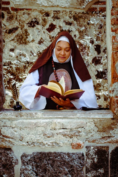 Foto profissional grátis de Bíblia, construção de pedra, freira sênior