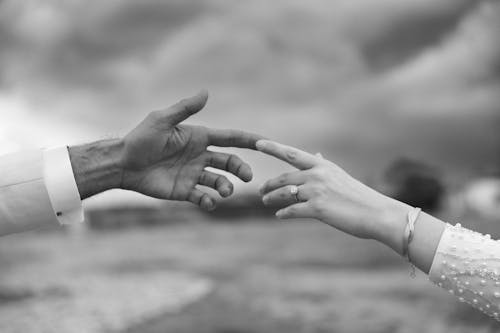 Black and white photo of a man and woman touching hands
