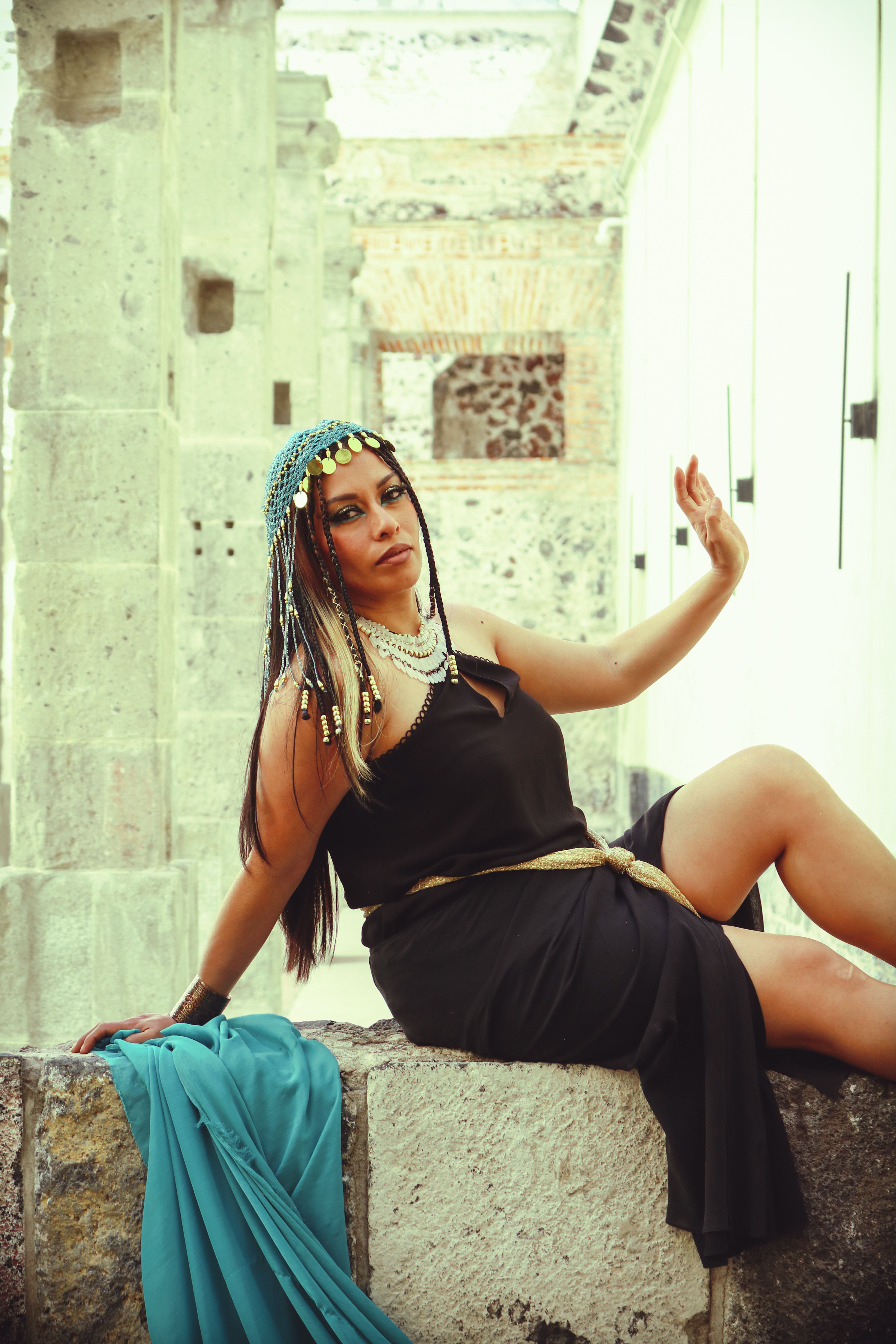 Woman in traditional attire posing against historic stone walls.