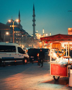 Vibrant street scene in Istanbul at night, featuring a mosque and bustling street vendor.