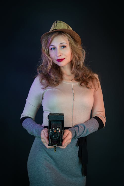 A woman in a hat holding an old camera