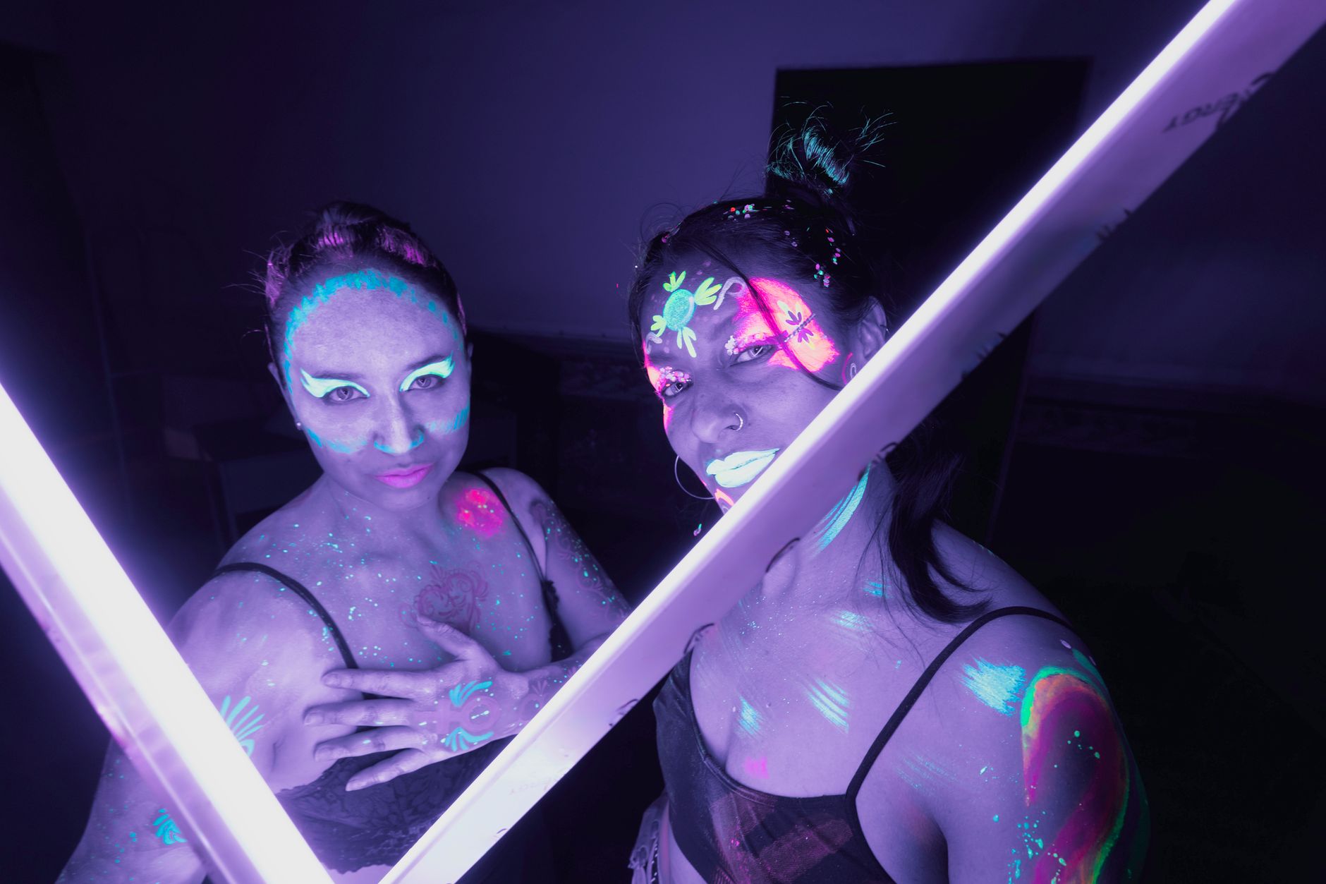 glow in the dark party cairo — A striking display of UV body paint on two women under neon lighting in Mexico City.