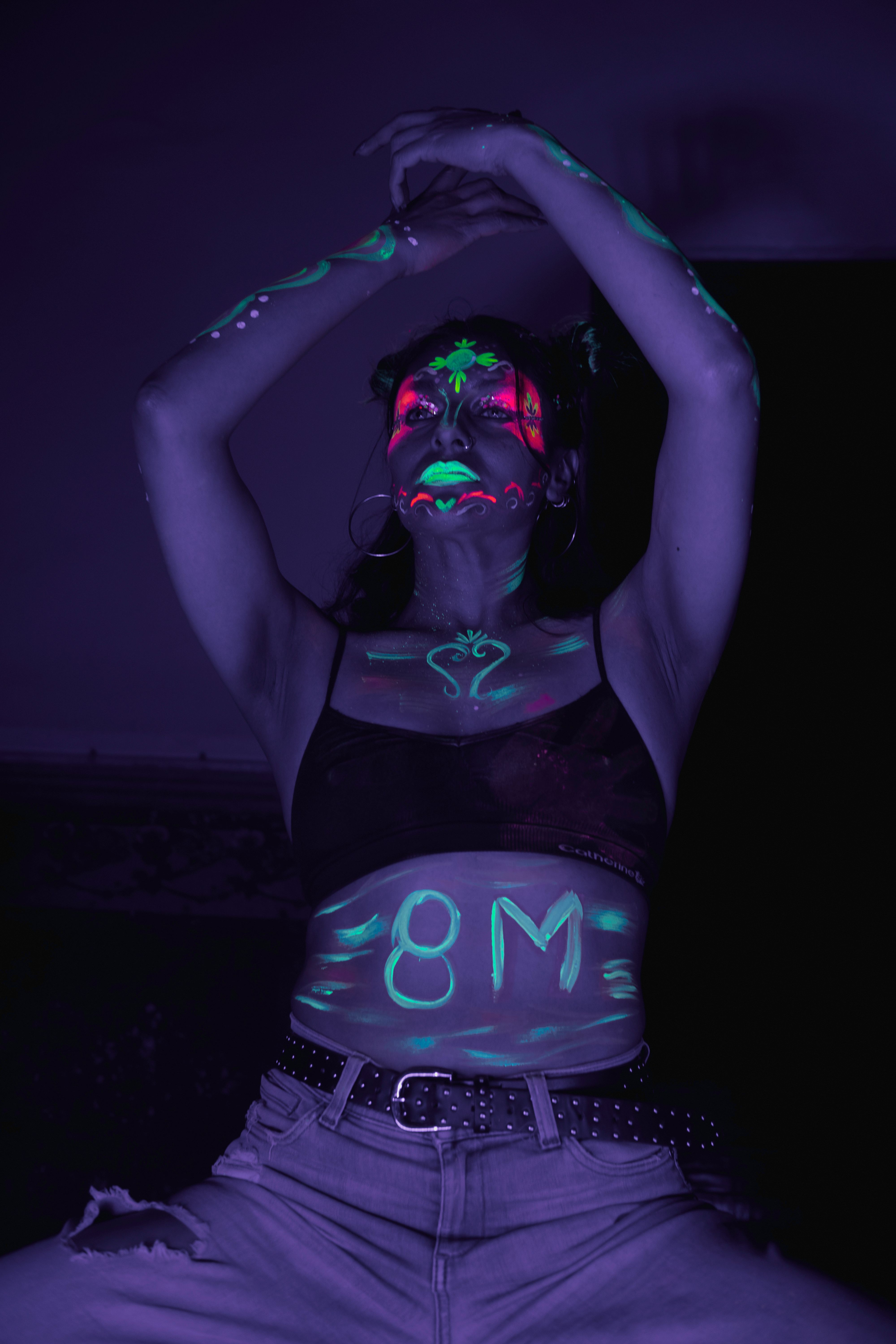 A woman in glowing UV body paint poses in Mexico City, celebrating empowerment with vibrant colors.