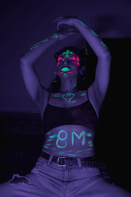 A woman with her hands up in the air and a neon sign that says gm