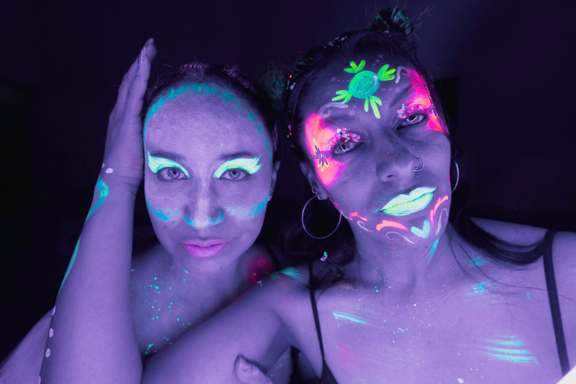 glow in the dark party cairo — Creative neon face paint on women creating vibrant, glowing portraits in Mexico City nightlife