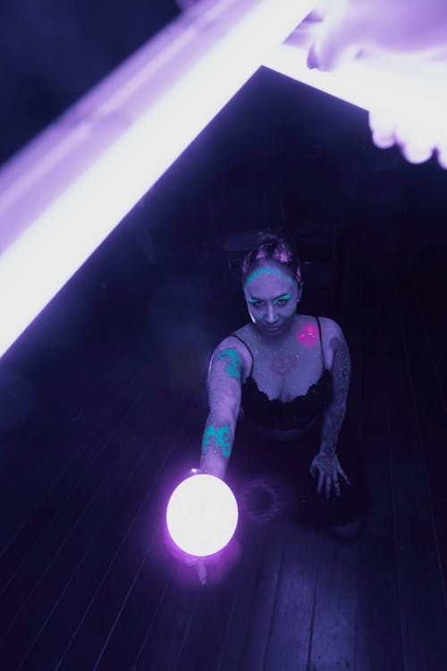 A woman with tattoos holding a purple light