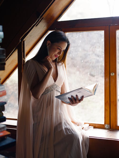 A woman in a long dress is reading a book