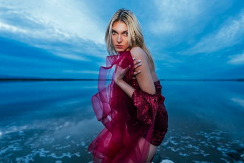 Blonde Woman Posing in Pink Dress by the Shore 
