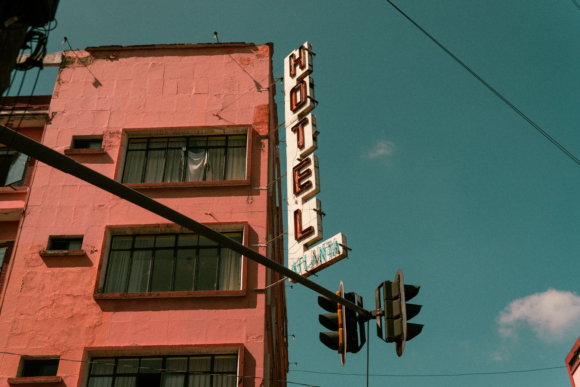 Vintage red hotel building with neon sign against bright turquoise sky, Atlanta
