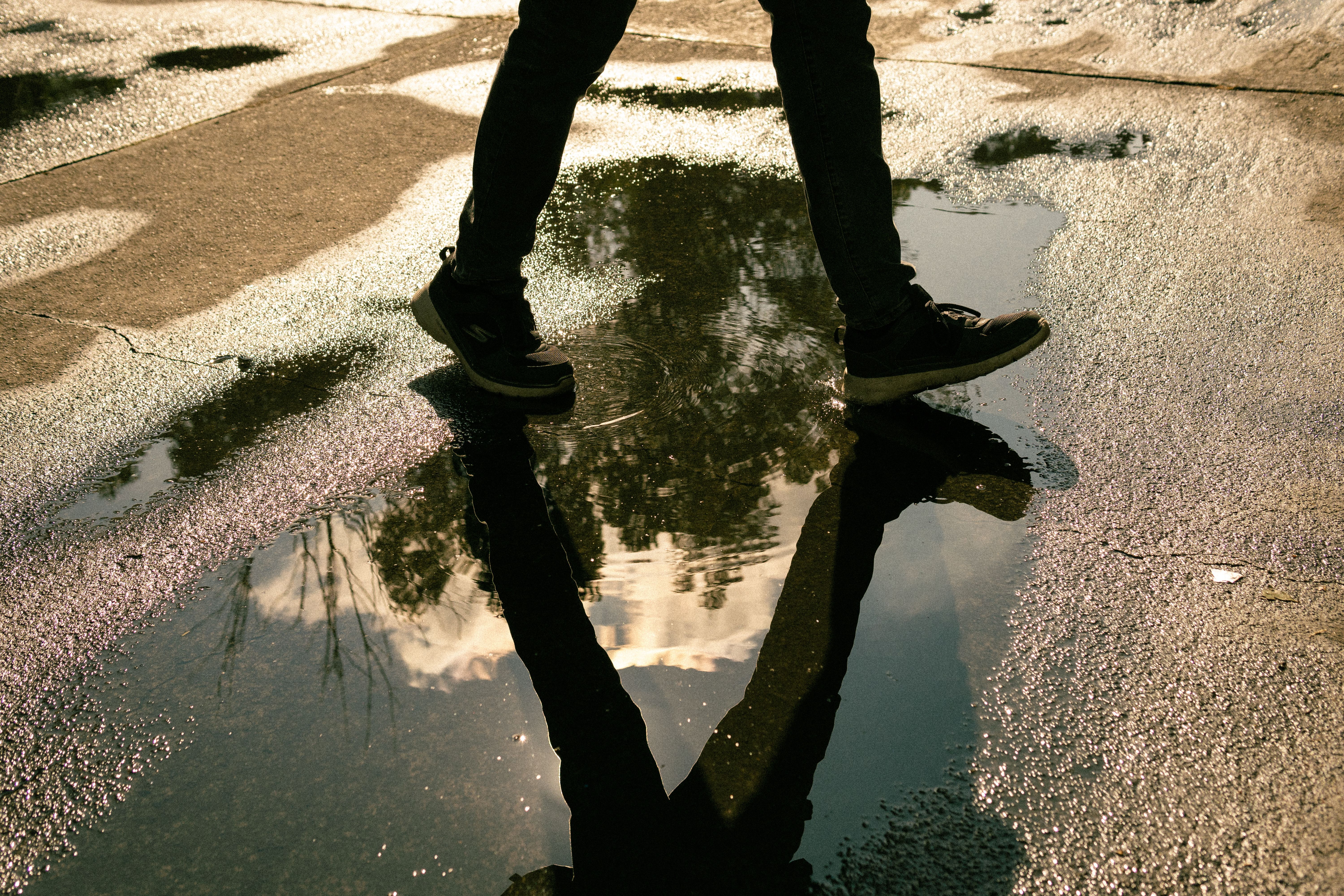 A person walks on a wet street in Mexico City, capturing a vivid reflection in a puddle.