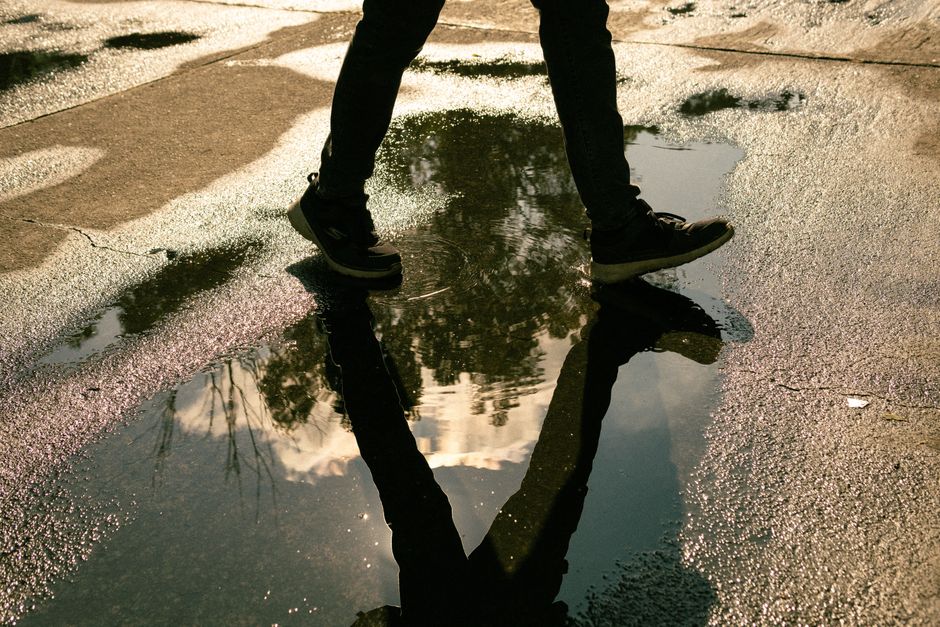 A person walks on a wet street in Mexico City, capturing a vivid reflection in a puddle. A person walks on a wet street in Mexico City, capturing a vivid reflection in a puddle.