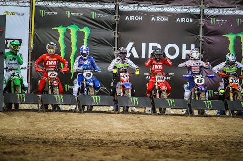 A group of dirt bike riders standing on a dirt track