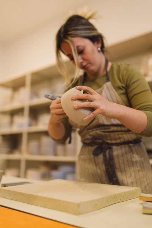 A woman is making a pottery bowl in a studio