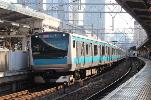 A sleek passenger train at a bustling Tokyo railway station showcasing urban travel.