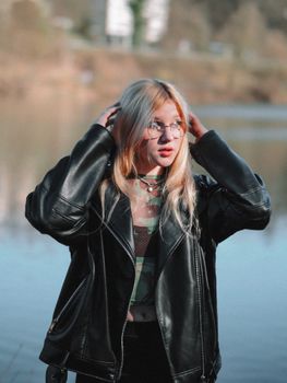 Portrait of a stylish teenage girl in a leather jacket by a lake, embracing casual fashion.