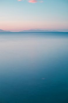 A peaceful ocean view during dusk with a calm horizon and soft pastel skies.