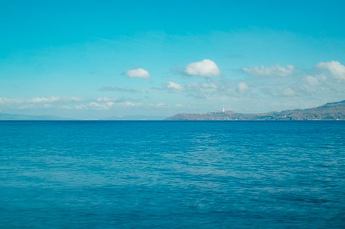 Free Peaceful ocean view with distant coastal mountains under a blue sky. Stock Photo