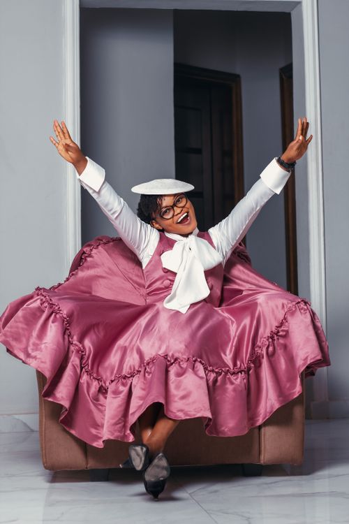A woman in a pink dress and hat is sitting on a chair · Free Stock Photo