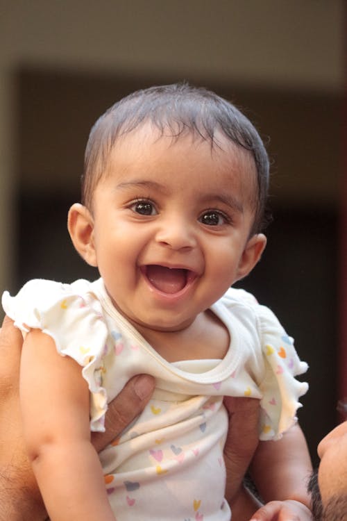 A smiling baby is holding a toy in her hand