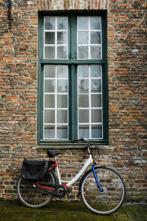 Free A classic bicycle rests against a historical brick wall in Brugge, Belgium. Stock Photo