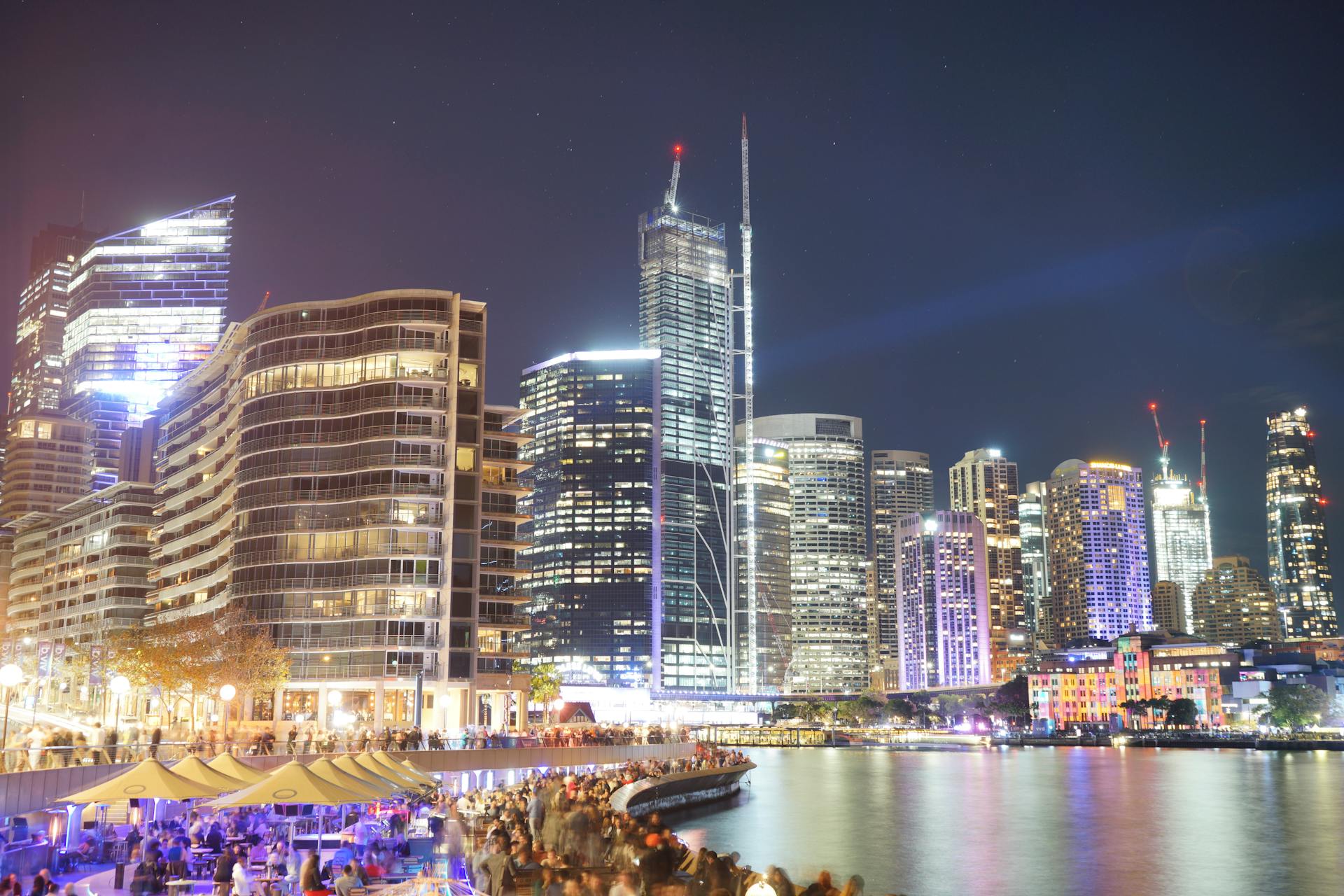 Illuminated skyline of Sydney featuring modern skyscrapers and waterfront promenade at night.