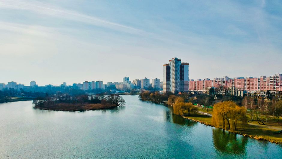 Drone view of Minsk's modern skyline, river, and park in fall.