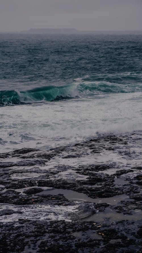 A photo of the ocean with waves crashing on the rocks