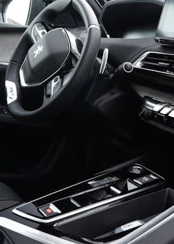 Close-up of a modern Peugeot car dashboard and steering wheel, highlighting advanced features.