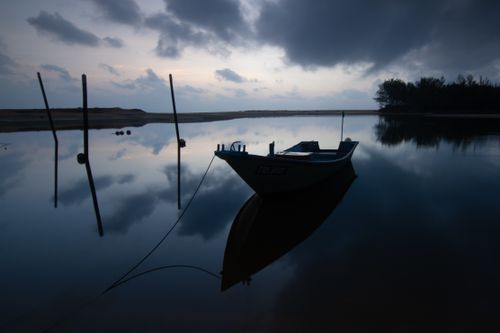 Free A serene scene of a boat at dusk on a calm lake, creating a peaceful and reflective atmosphere. Stock Photo