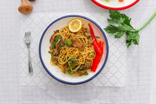 Free Appetizing top-view of spaghetti with vegetables and lemon slice, perfect for culinary presentations. Stock Photo