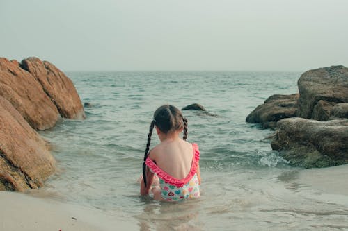 A little girl sitting in the water on a beach