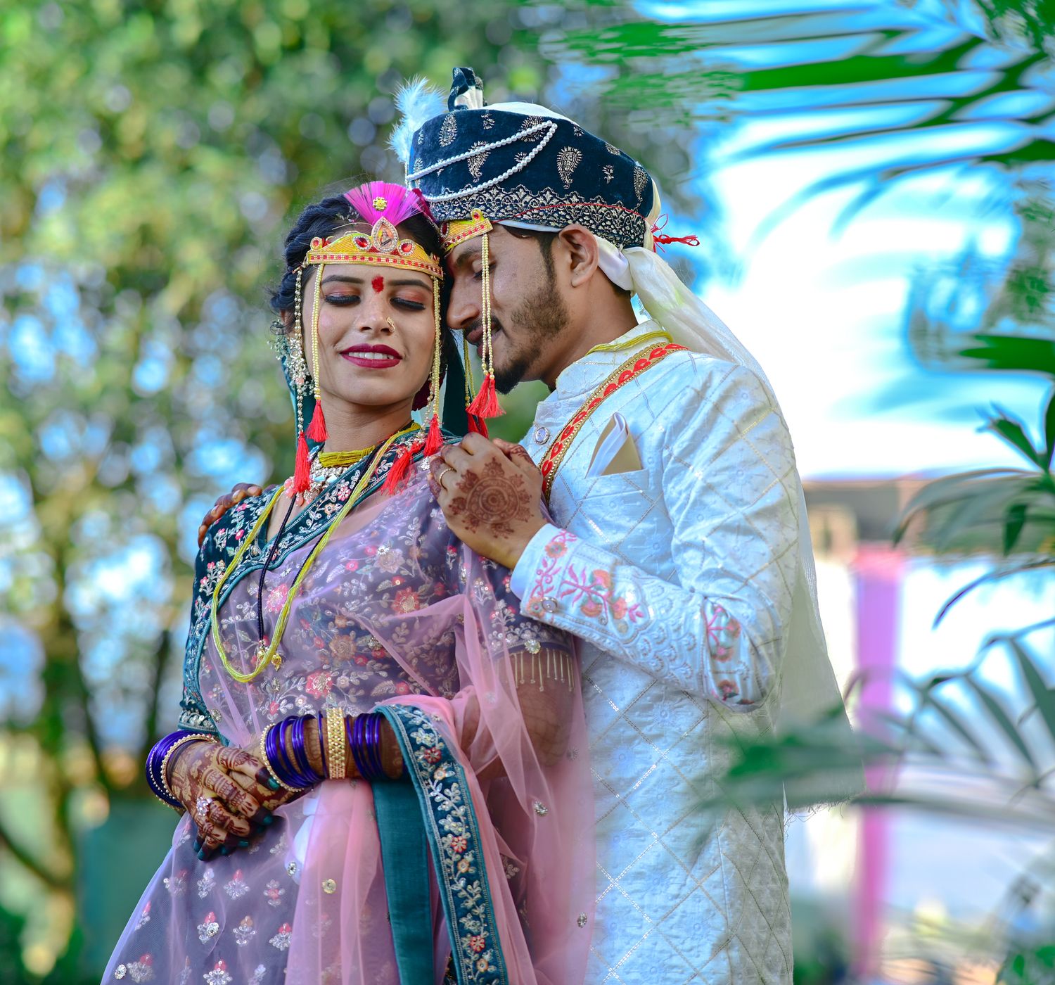 A happy couple in traditional Indian attire, celebrating their wedding outdoors.