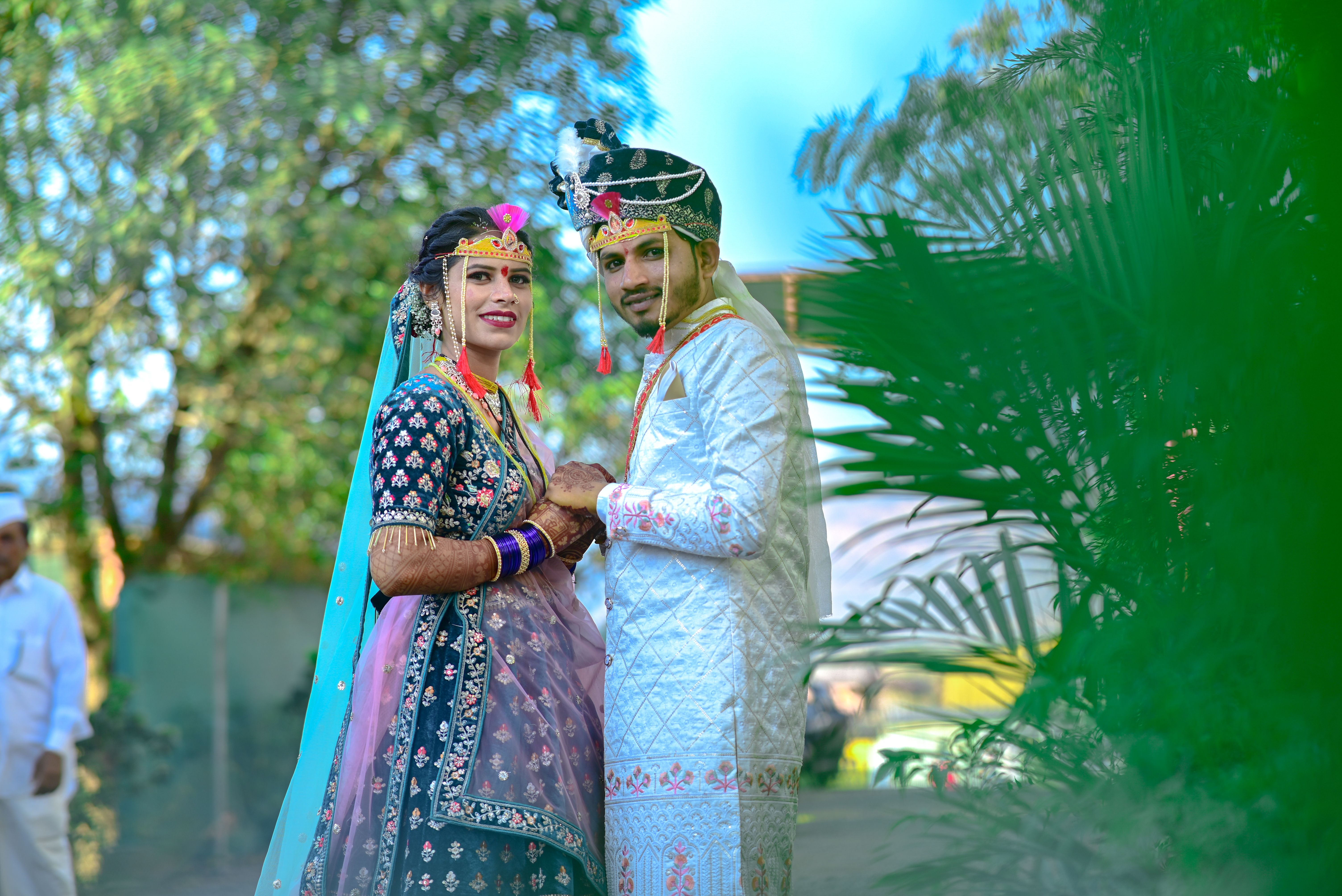 A joyful Indian couple in traditional attire celebrating their wedding outdoors.