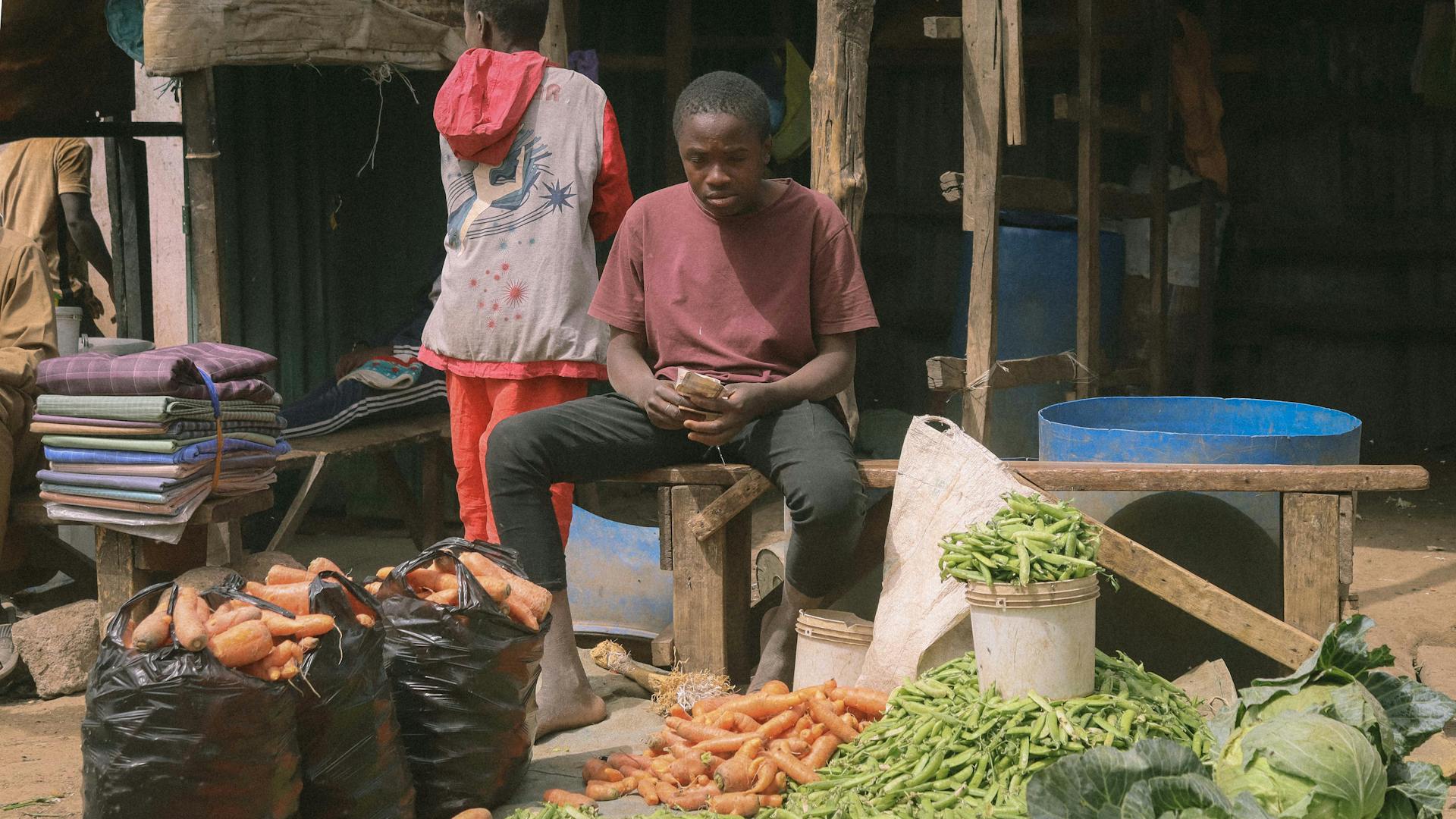 A young seller managing vegetables at a local market in Kaduna, Nigeria.