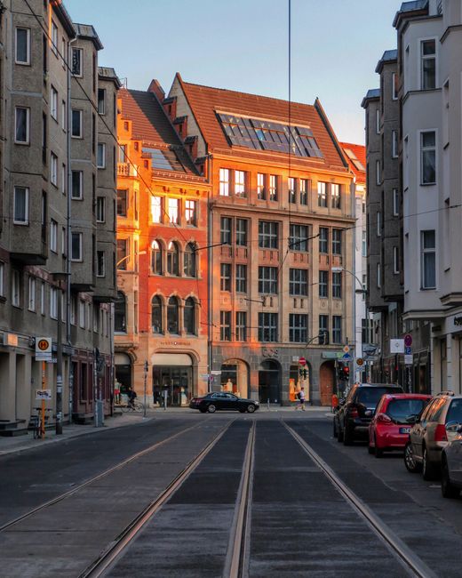 Charming Berlin city street with parked cars and classic architecture at sunset.