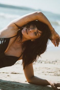 An elegant woman with brunette hair posing naturally on a sunny beach, evoking a sense of relaxation.