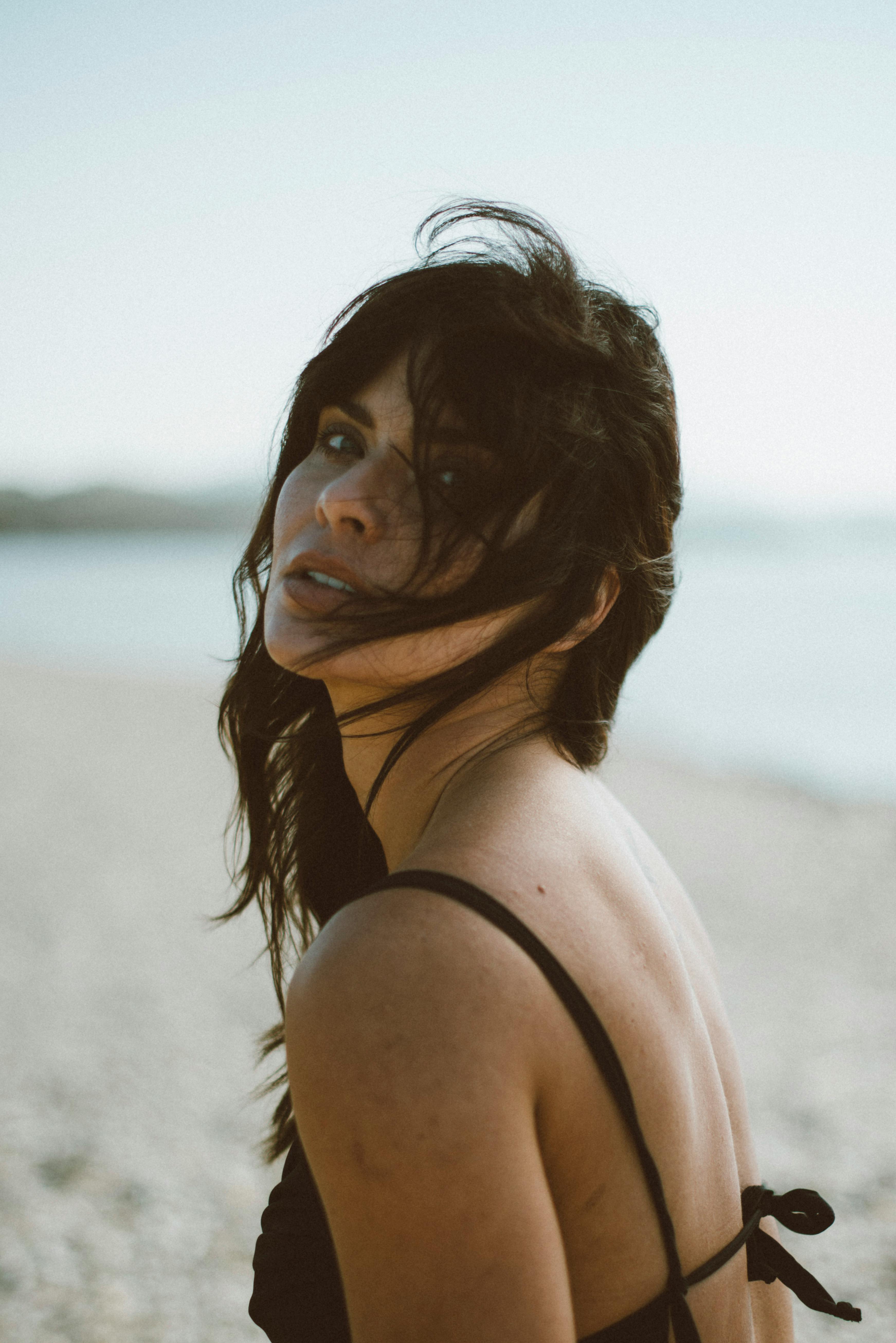 这是一幅宁静的肖像，描绘了一位白天在沙滩上享受海风的女子